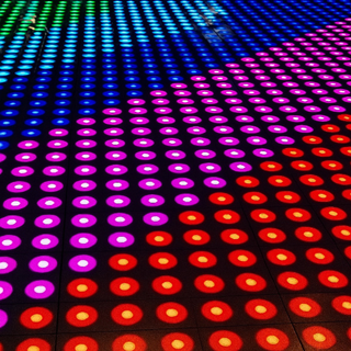 LED-dansvloer met patronen in groen, blauw, paars en rood tegen donkere achtergrond LED-dansvloer met patronen in groen, blauw, paars en rood tegen donkere achtergrond